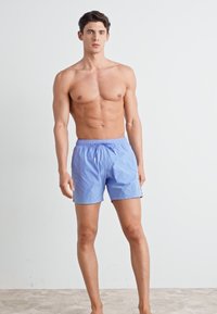 Shorts de bain bleu clair en tissu à séchage rapide ; taille élastique avec cordon de serrage ; coupe décontractée ; sans motifs ni accents supplémentaires.