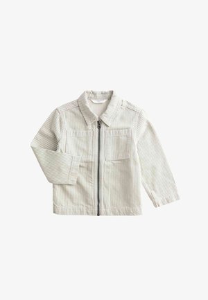 Lysegrå og hvide stribede jakke med lynlås foran, kombineret med en pink sweatshirt. Modellen smiler og har matchende stribede bukser på.