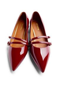 Ein Paar glänzende burgunderrote Ballerinas mit spitzen Zehen, doppelten Riemen und kleinen Schnallen, hellbraunen Einlegesohlen, von oben auf einem weißen Hintergrund gezeigt.