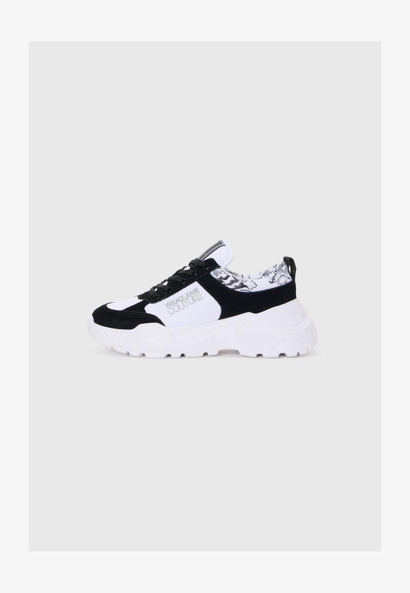 Svart og hvit sneaker med en solid hvit såle, laget av semsket skinn og mesh-materialer, snøring, og et mønstret innerfôr.