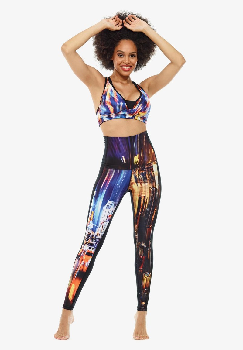 Bunte Sport-BH und hochgeschnittene Leggings mit Drucken von urbanen Nachtlandschaften. Hergestellt aus dehnbarem, atmungsaktivem Material mit einer glatten Textur.