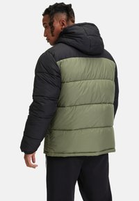 Puffjacka med en svart övre del och en olivgrön nedre del, med horisontella quiltade paneler och en huva.