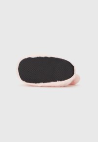 Lys rosa fluffy hjemmesko med en sort tekstureret sål, rund form og blødt pelslignende materiale langs kanterne.