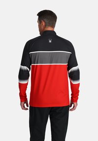 Camicia a maniche lunghe rossa, nera e grigia con righe orizzontali. Presenta un logo a forma di ragno sul retro e un tessuto liscio e testurizzato.