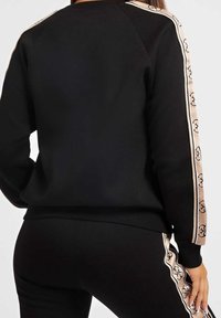 Sudadera negra con mangas a rayas beige y logo. Presenta un cuello redondo y puños acanalados. Diseño ajustado hecho de un material suave.