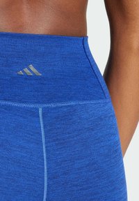 Leggings sportivi blu in tessuto testurizzato e melangiato. La vita è alta e presenta un'accento del logo sottile in argento.