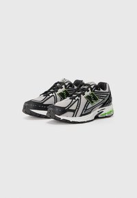 Paire de chaussures de course grises et noires avec des accents verts et un amorti visible sur fond blanc.