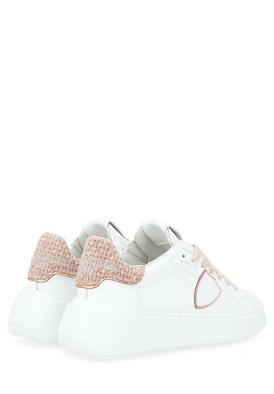 Sneakers bianchi con una trama di patch rosa chiaro sul tallone, dettagli in oro rosa e una suola piatta in gomma liscia.