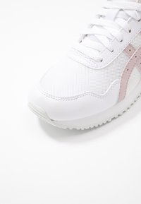 Vitaid sportskor med en strukturerad mesh-överkonstruktion, rosa detaljer och gummisula. Har snörning och en rundad tådesign.