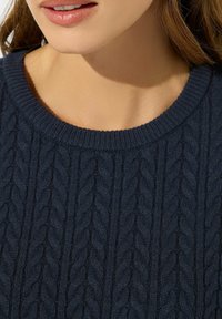Suéter de punto azul marino con un patrón de cableado texturizado, cuello ancho de canalé y tejido suave, adecuado para mantener el calor y la comodidad.