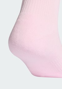 Roza gležnjska nogavica z rebrasto teksturo, gladkim materialom in tesnim prileganjem pri peti, ki prikazuje čist in preprost dizajn.