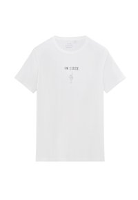 Camiseta de algodón blanca con mangas cortas, que presenta un gráfico impreso de una mano levantada y el texto "EN ESCENA" en negro. Diseño de cuello redondo.