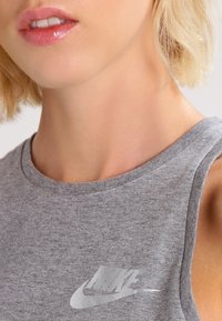 Grå, ärmlös träningslinne tillverkat av mjuk bomullsblandning, med en reflexerande Nike-logotyp på framsidan och rundad halsringning.