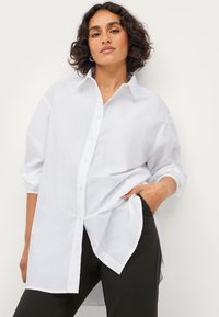 Witte button-up shirt van lichtgewicht stof, met een klassieke kraag, lange mouwen en een losse pasvorm met een gebogen zoom.