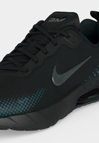 Μαύρο αθλητικό παπούτσι Nike Air Max για τρέξιμο με μπλε πουά σχέδιο κοντά στην μύτη, μαύρα κορδόνια και ορατή απορρόφηση κραδασμών Air Max στη σόλα.