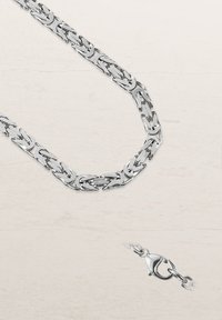 Silberner Kettenanhänger mit miteinander verbundenen Gliedern, mit einem polierten Finish und einem Karabinerhaken. Das Muster ist geometrisch und einheitlich.