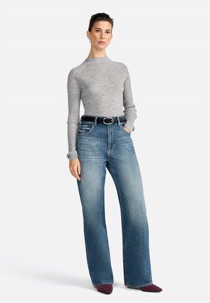 Maglioncino grigio a costine con maniche lunghe, jeans a vita alta in denim blu a gamba larga, cintura nera con fibbia rotonda, scarpe a punta bordeaux.