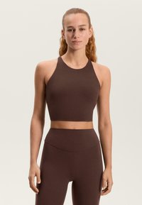 Barna, testhez simuló, magas nyakú és széles pántú crop top, sima anyagból készült. Magas derekú hozzáillő alsóval párosítva.