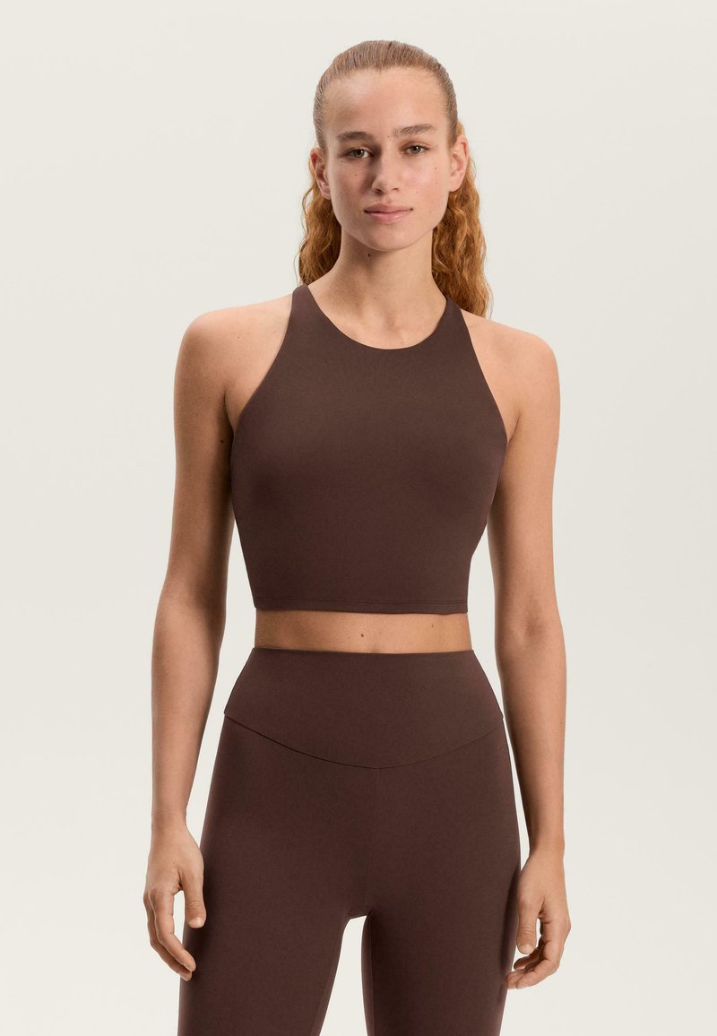 Barna, testhez simuló, magas nyakú és széles pántú crop top, sima anyagból készült. Magas derekú hozzáillő alsóval párosítva.