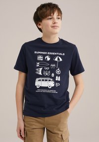 Marinblå t-shirt med vita grafiska tryck av sommarartiklar, inklusive en skåpbil, surfbräda och strandaccessoarer, med text högst upp och längst ner.