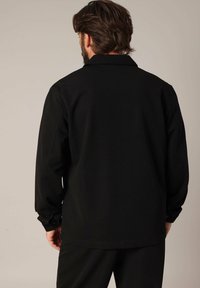 Zwart lange mouwen shirt met een platte kraag, gemaakt van een glad materiaal, met knoopmanchetten en een comfortabele pasvorm.