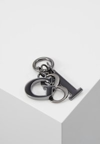 Metal nøglering med sammenkædede bogstaver "G" og "L" i mørk metallisk finish. Glat tekstur med en blank overflade, fastgjort til en cirkulær ring.