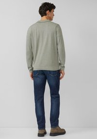 Lichtgroen gestreept poloshirt met lange mouwen, gecombineerd met donkerblauwe jeans en bruine laarzen; heeft een klassieke kraag en geribbelde manchetten.