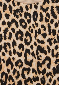 Megztas audinys su leopardų raštu juoda spalva ant smėlio spalvos fono, su ryškiais dėmėmis ir švelnia tekstūra. Matoma apvalios iškirptės detalė.