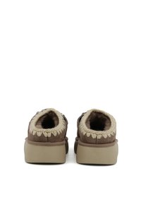 Scarpe slip-on in suede marrone con bordi lavorati a maglia beige, dotate di una morbida fodera interna e una resistente suola in gomma chiara.