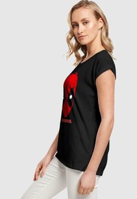 Tricou negru cu un grafic mare roșu al lui Deadpool și accente albe. Mâneci scurte, croială clasică, din material de bumbac moale.