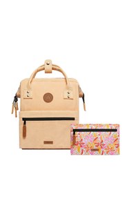 Zaino in corduroy di un morbido color pesco con maniglia superiore, tasca frontale con zip e dettagli in pelle, abbinato a una pochette con zip a motivi colorati in rosa e arancione.