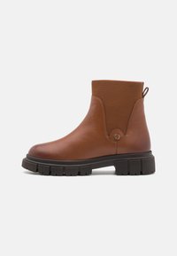 Bottine en cuir marron avec panneau latéral élastique, bout arrondi et semelle en caoutchouc texturée présentant un profond relief pour une bonne adhérence.