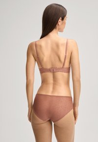 Set di lingerie marrone con reggiseno in pizzo dotato di spalline regolabili e slip coordinati con un motivo floreale e bordi smerlati.