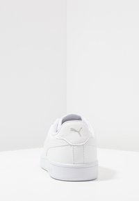 Sneaker bianco con tomaia in pelle liscia, colletto imbottito e suola testurizzata. Presenta un discreto logo grigio sul tallone e semplici dettagli di cucitura.