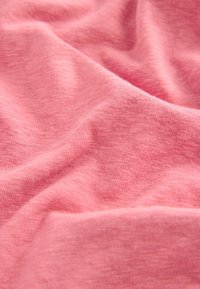 Rosa Strickstoff mit einer weichen, strukturierten Oberfläche, die ein dezentes meliertes Muster und sanfte Falten aufweist, wodurch ein fließendes Erscheinungsbild entsteht.