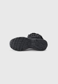 Black winter boot with textured rubber sole and fur lining, positioned sole-up against a light gray background.