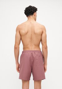 Vyrų maudymosi šortai, dulkėtos rožinės spalvos, elastingas juosmuo, užpakalinis kišenė, lygus audinys, iki vidurio šlaunų ilgio, minimalistinio dizaino.