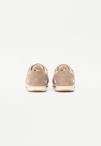 Beige nubuk sneakers med perforerte detaljer, lyse såler og polstrede hæler. Minimalistisk design, egnet for ulike uformelle anledninger.