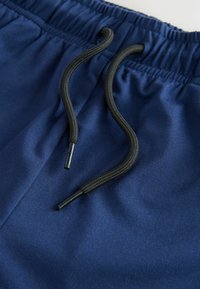 Shorts bleu marine avec une taille élastique et un cordon de serrage noir. Tissu doux avec une texture lisse et des détails de design minimalistes.