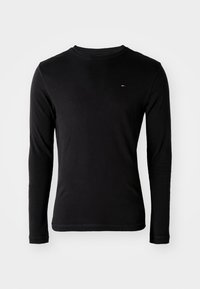 Schwarzes, langärmeliges, figurbetontes Rundhals-T-Shirt mit kleinem rot, weiß und blau horizontalem Logo auf der linken Brust vor weißem Hintergrund.