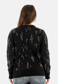 Suéter negro con un tejido texturizado, que presenta acentos de patrón vertical blanco y un dobladillo de canalé. Diseño clásico de cuello redondo.