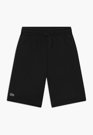 Pantalones cortos negros de algodón con cintura elástica y cordón. Presentan un pequeño logo verde de Lacoste en la pierna izquierda. Textura suave, diseño casual.