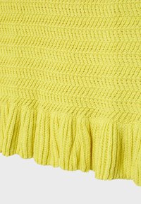 Tissu tricoté jaune avec un motif en zigzag texturé et un large volant côtelé le long du bord inférieur.