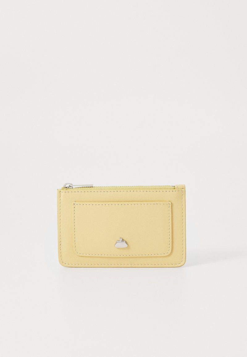 Dzeltena ādas kredītkaršu turētāja ar priekšējo kabatu, sudraba piederumiem un gludu vīli. Kompakta konstrukcija ar gludu tekstūru.