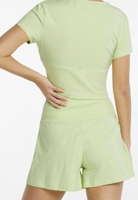 Hellgrünes T-Shirt mit kurzen Ärmeln und gerippten Akzenten; kombiniert mit hellgrüßen Shorts. Weicher, dehnbarer Stoff. Einfaches, lässiges Design.