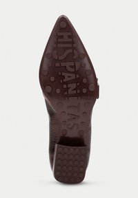 Suola di scarpa in pelle con un design affusolato. Colore marrone scuro, superficie testurizzata, punti in gomma per la presa e dettagli del marchio impressi.