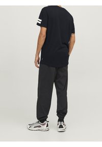 Marinblå t-shirt med vita ränder på ärmarna, ihop med svarta byxor. Byxorna har elastiska mudd och avslappnad passform. Styla med vita och grå sneakers.