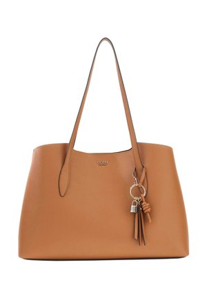 Sac cabas en cuir beige avec deux anses, logo GUESS en métal et porte-clés décoratif avec pompon et petit cadenas.