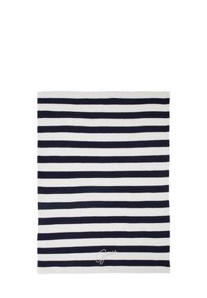 Prostokątny tekstyl z poziomymi czarno-białymi paskami i małym białym wyszywanym podpisem blisko dolnej krawędzi.
