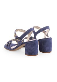 Navyblauwe suede sandalen met hakken en een open ontwerp, voorzien van metalen accenten, verstelbare banden en een chunky blokhak.